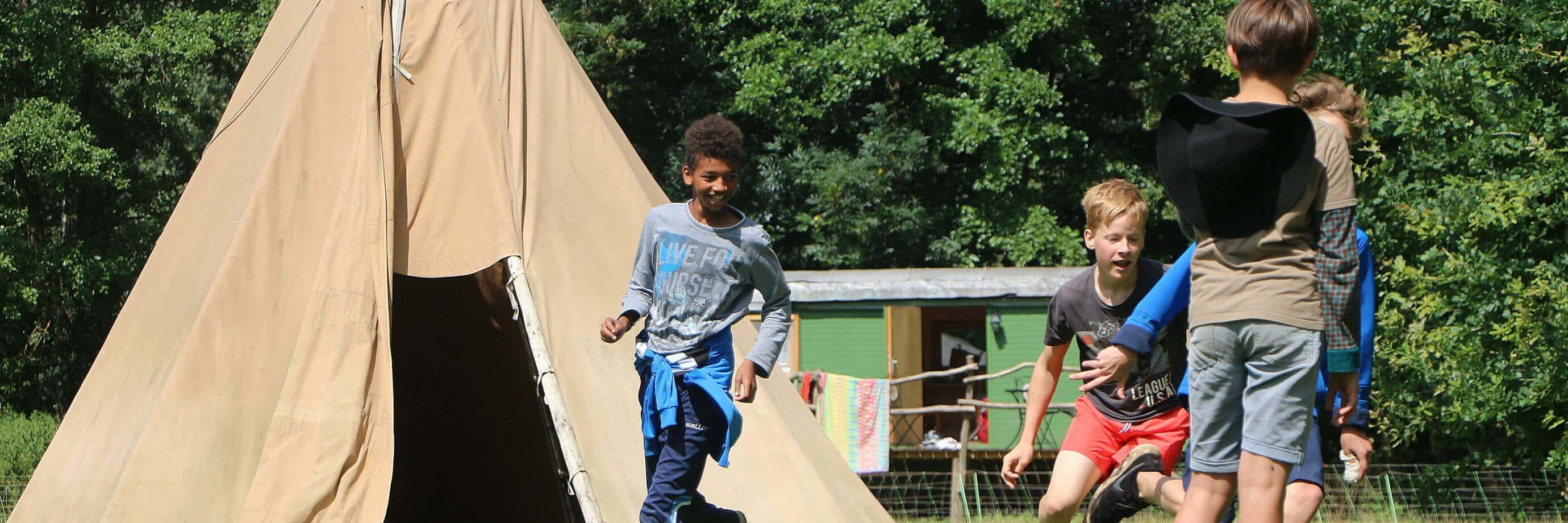 Kinder spielen neben einem Zelt