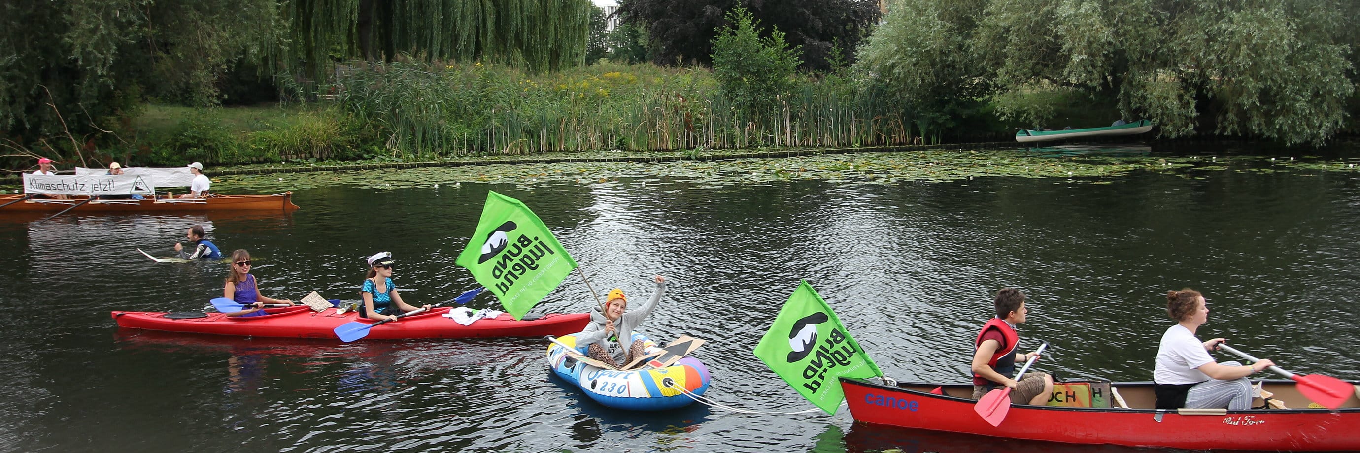 Paddelboote mit Umweltschutz-Bannern auf einem Fluss