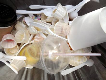 Plastikbesteck und -becher im Müllbehälter.